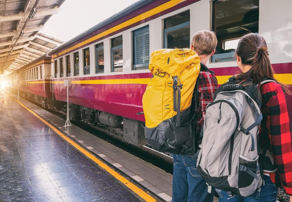 couple waiting for train with backpacks traveling europe
