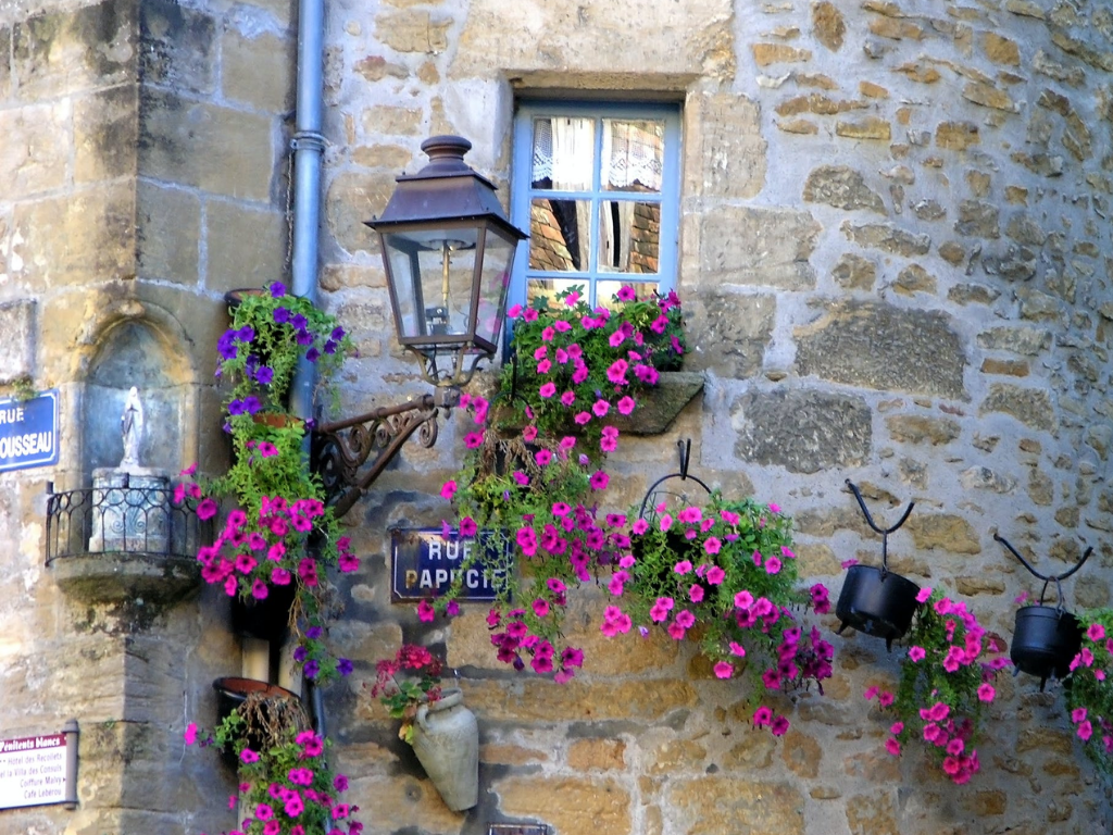 stone walls with pink flower pots hanging