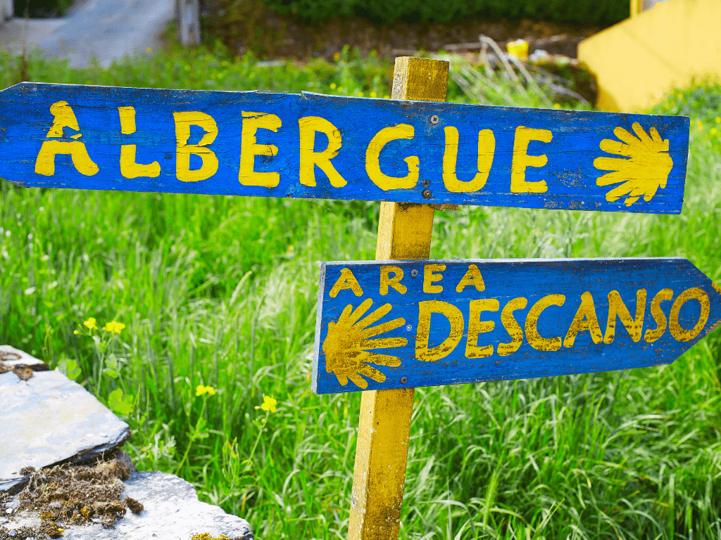 blue and yellow signs pointing to albergues on the camino de santiago