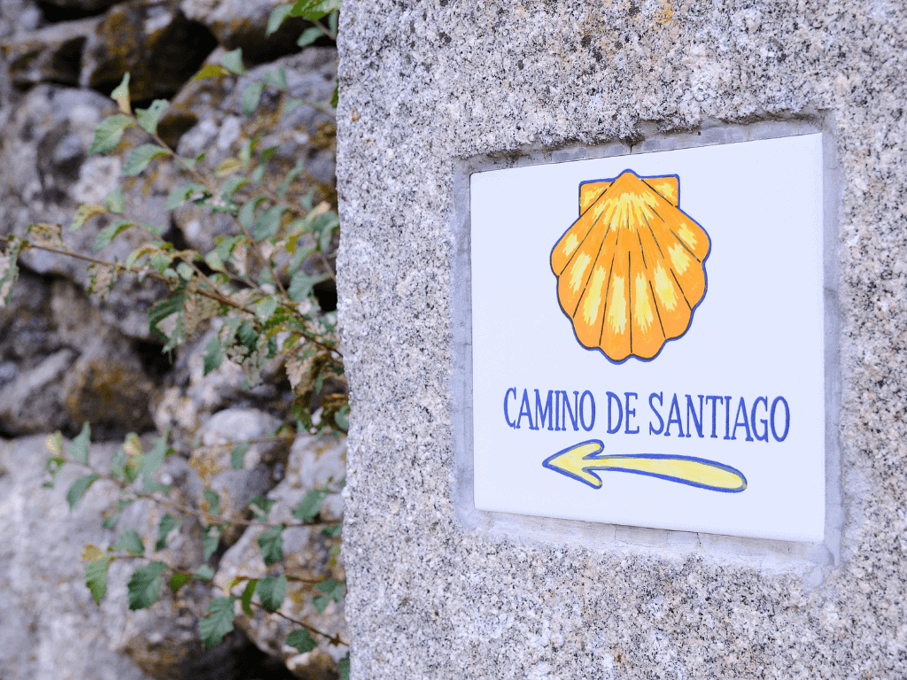 waymarker on the camino de santiago with a tile with a yellow shell and arrow