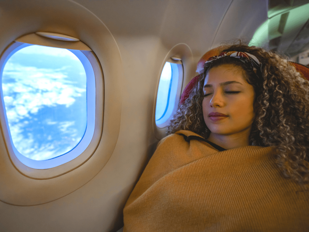 girl sleeping next to open plane windows