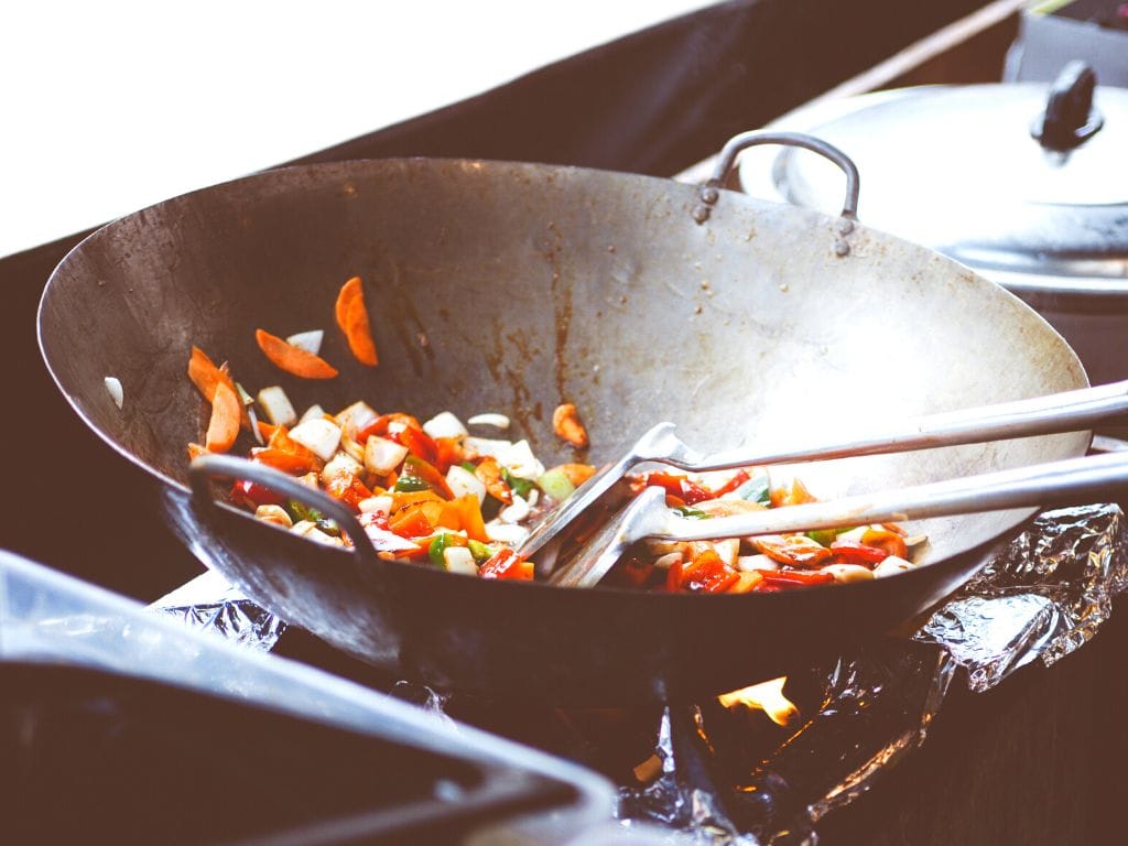 a wok full of veggies on a stove