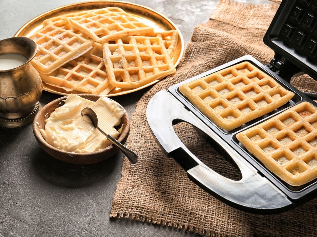 waffles on a plate with more cooking on a waffle iron