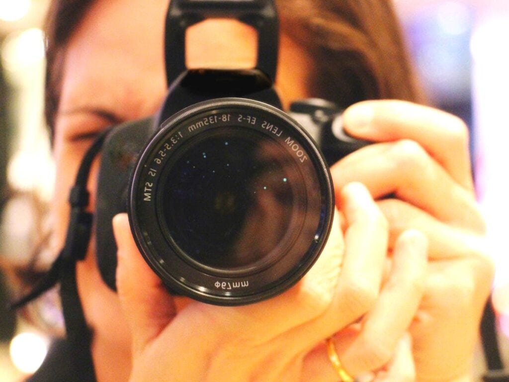 woman holding a camera to her face so you can only see the camera lense